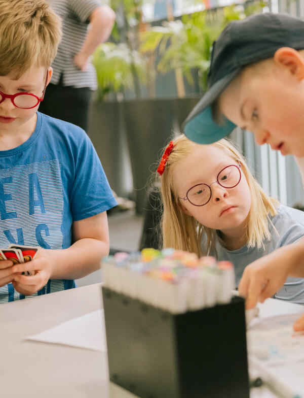 Kinder zeichnen und spielen an einem Tisch.